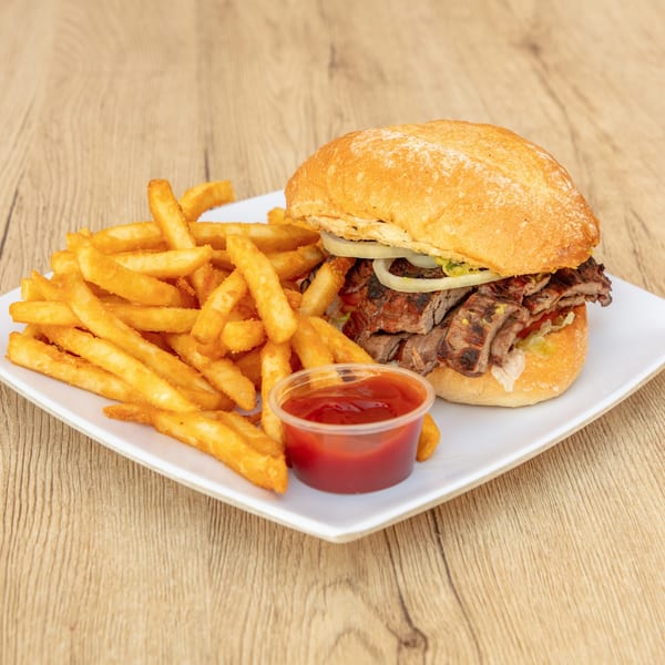 Grilled steak sandwich with onions and lettuce, served with golden french fries and ketchup.