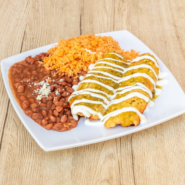 Two enchiladas with green sauce and sour cream, served with rice and beans on a white plate.