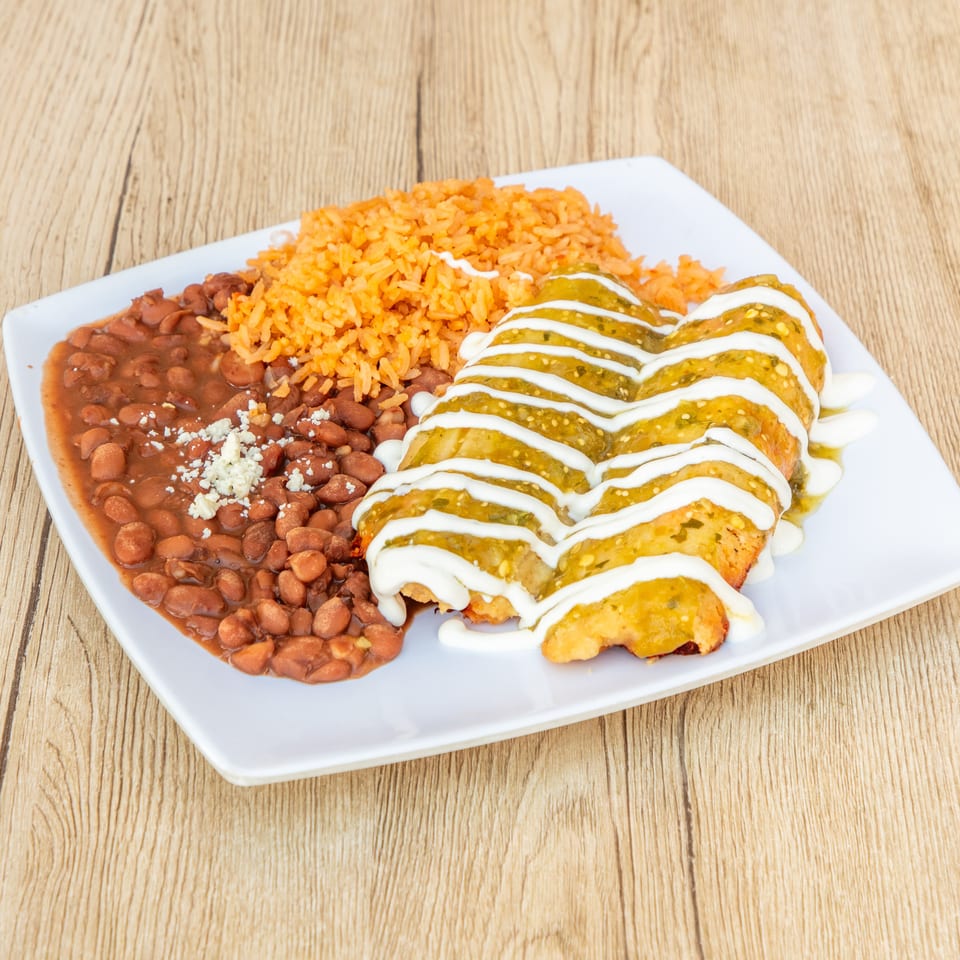 Two enchiladas with green sauce and sour cream, served with rice and beans on a white plate.